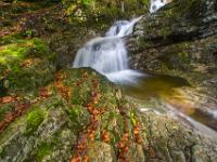 Herbstlaub auf gestuftem Fels vor Wasserfall - Weißenbach